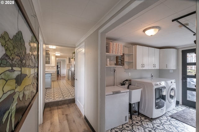 laundry room featuring sink, cabinets, washer and dryer, light wood-type flooring, and ornamental molding