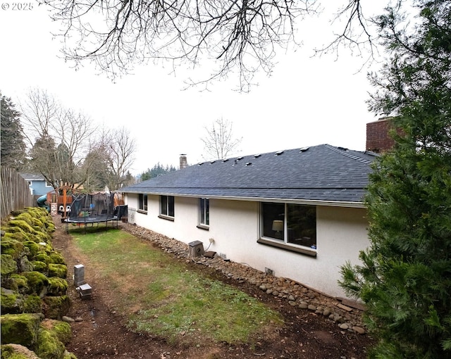 view of side of home with a trampoline and a lawn