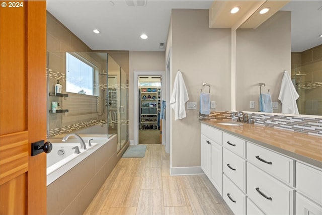 bathroom featuring tasteful backsplash, vanity, and plus walk in shower