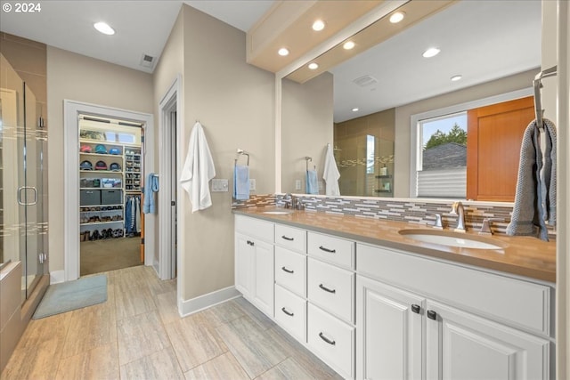 bathroom with vanity, an enclosed shower, and backsplash