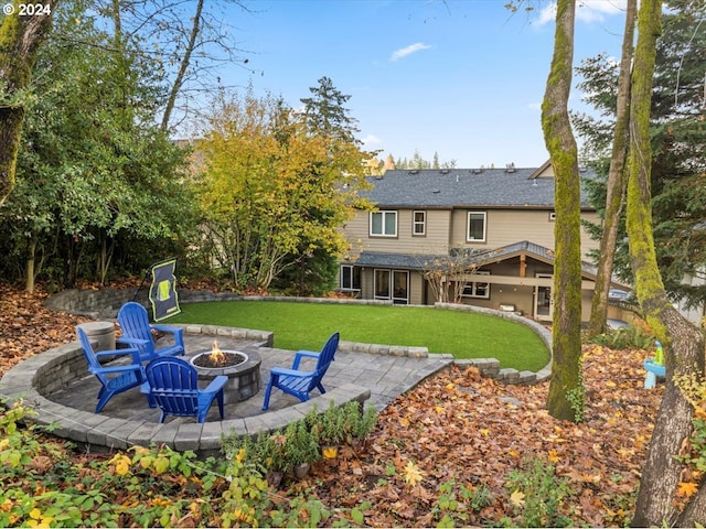 back of property featuring a fire pit, a lawn, and a patio area