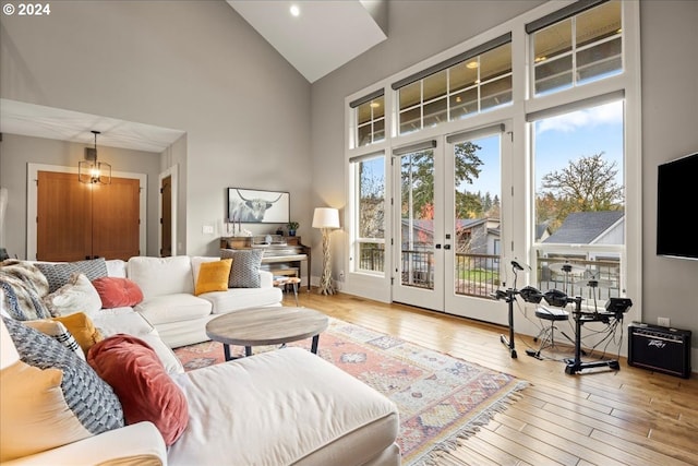 living room featuring wood-type flooring, high vaulted ceiling, and french doors