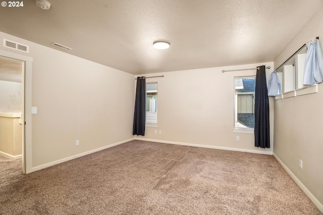 carpeted empty room with a textured ceiling