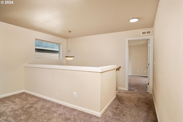 hallway with carpet flooring and a textured ceiling