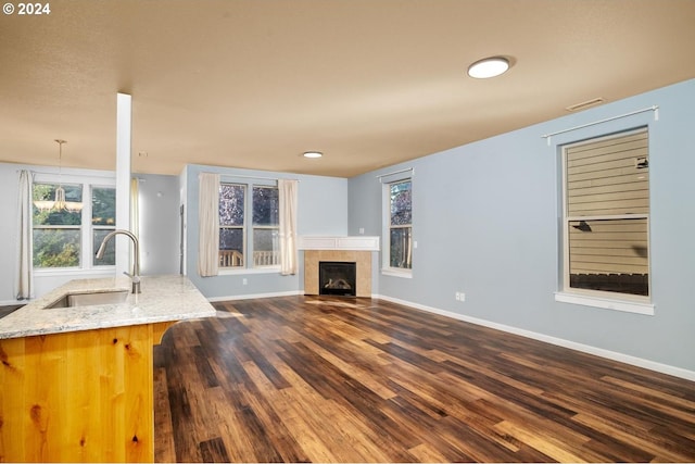 unfurnished living room featuring a fireplace, a notable chandelier, dark wood-type flooring, and sink