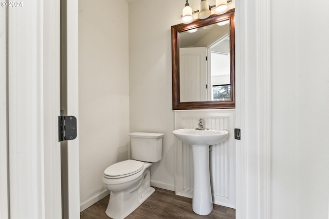 half bathroom with a sink, wood finished floors, toilet, and baseboards