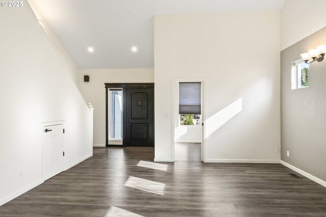 unfurnished living room featuring a high ceiling, ceiling fan, and dark hardwood / wood-style flooring