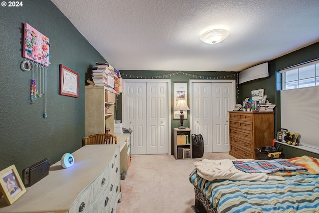 carpeted bedroom featuring a textured ceiling and two closets