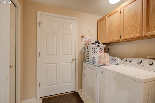 clothes washing area with dark tile patterned flooring, cabinets, and washing machine and clothes dryer