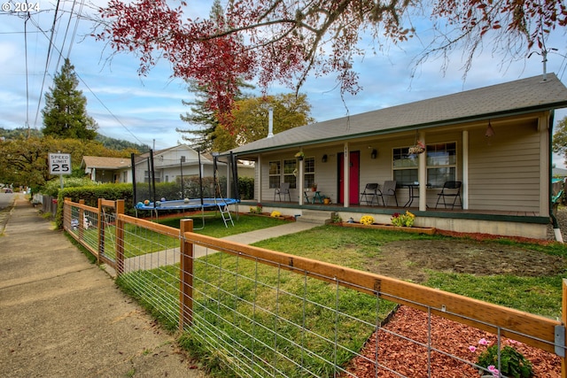 view of front of home featuring a porch, a trampoline, and a front lawn