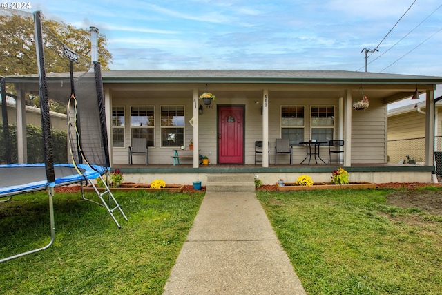 view of front of property featuring a porch, a trampoline, and a front lawn