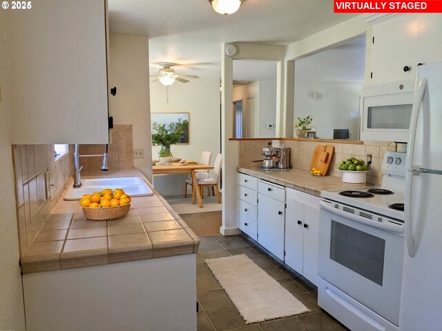 kitchen with tile counters, white cabinetry, tasteful backsplash, and white appliances