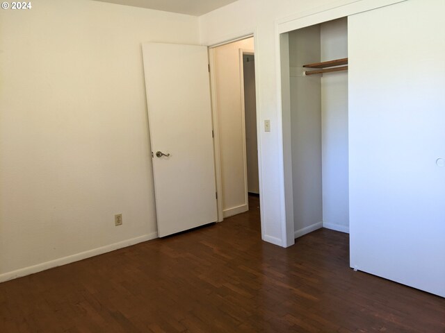 unfurnished bedroom with dark wood-type flooring and a closet