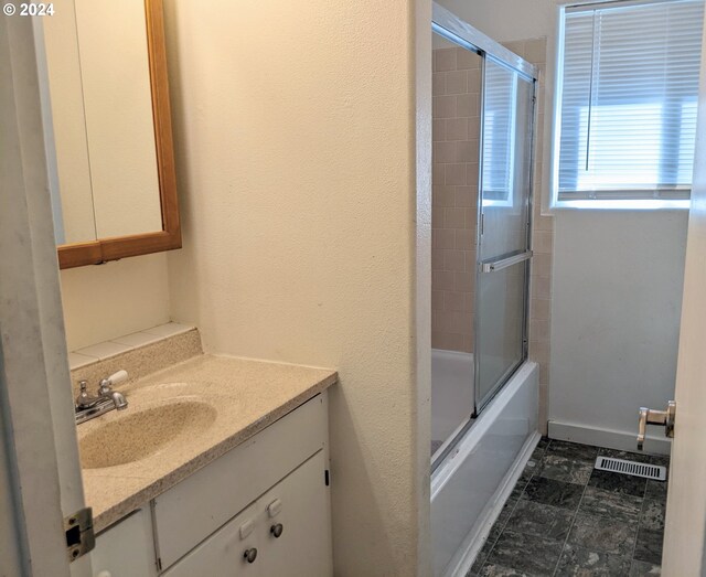 bathroom featuring enclosed tub / shower combo and vanity