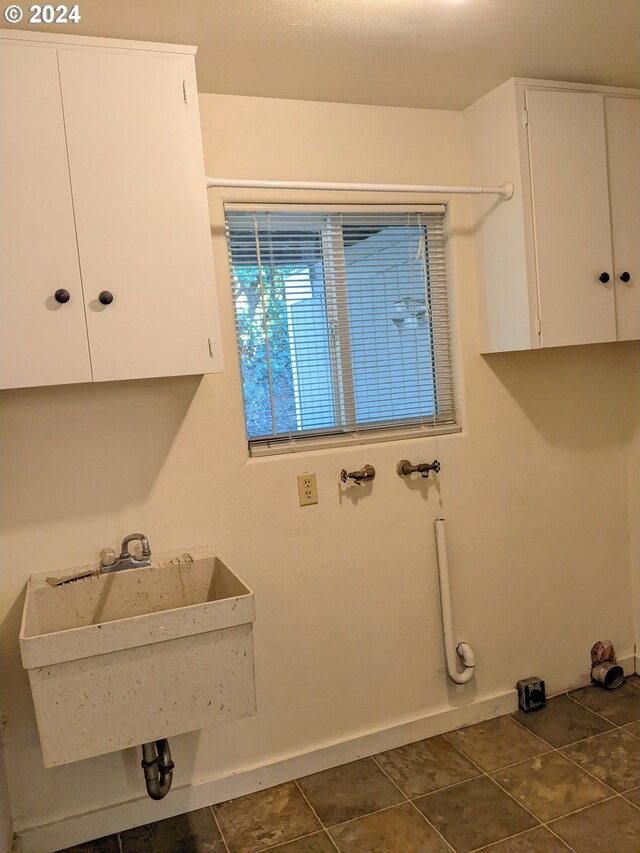 laundry area featuring cabinets, sink, and dark tile patterned floors