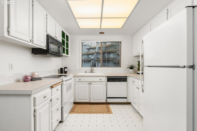 kitchen with sink, white appliances, white cabinets, and light carpet