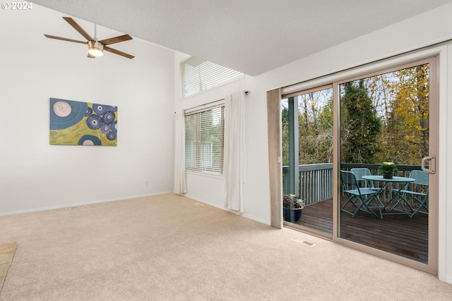 living room with a textured ceiling, light carpet, a wood stove, ceiling fan, and lofted ceiling