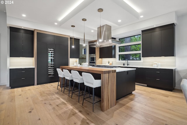 13581 Goodall Rd, Lake Oswego, OR 97034 - kitchen featuring dark cabinetry, island exhaust hood, modern cabinets, a breakfast bar, and recessed lighting