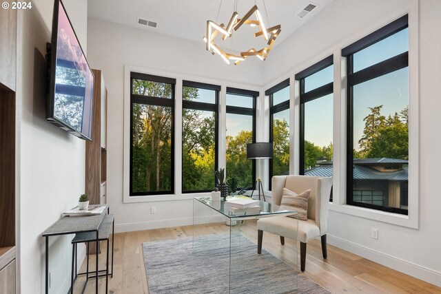 sitting room with a notable chandelier, a healthy amount of sunlight, and light hardwood / wood-style flooring