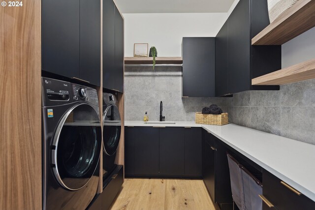 washroom with light hardwood / wood-style floors, cabinets, sink, and washing machine and clothes dryer