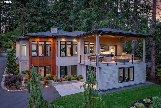 rear view of house with a patio, a balcony, and a lawn