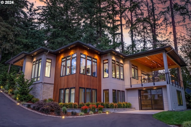 exterior space with aphalt driveway, a balcony, and a garage