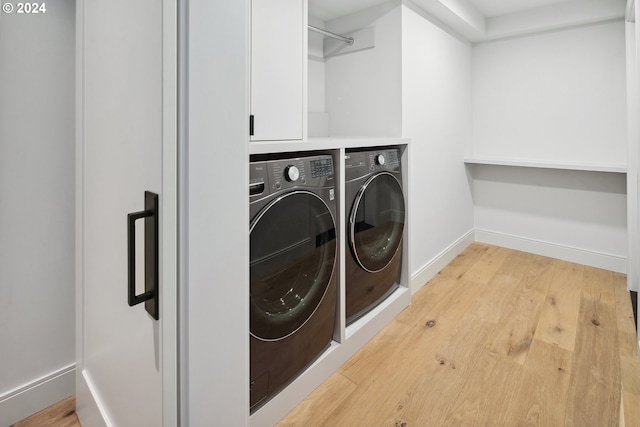 laundry room with washing machine and dryer and light hardwood / wood-style floors