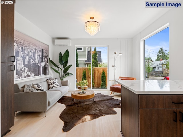 living area featuring healthy amount of natural light, an AC wall unit, light wood-type flooring, and a chandelier