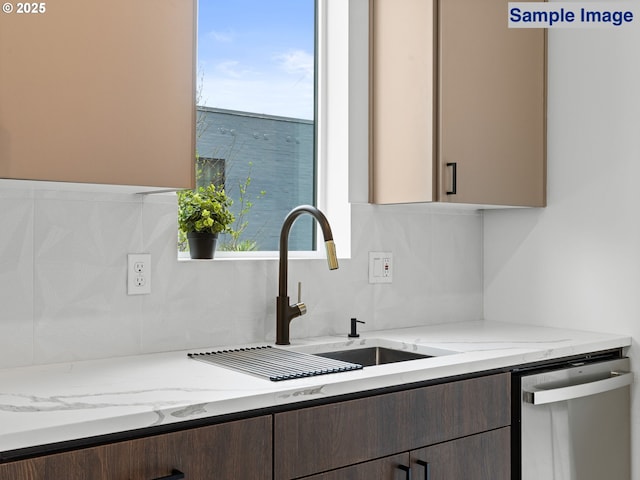 kitchen featuring stainless steel dishwasher, a sink, decorative backsplash, and light stone counters