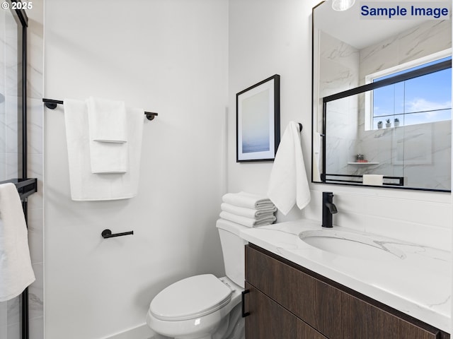 bathroom featuring vanity, a shower with shower door, and toilet