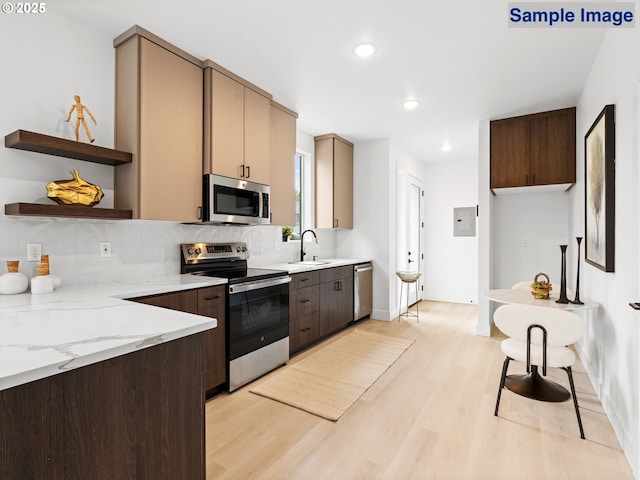 kitchen featuring appliances with stainless steel finishes, a sink, light wood-style flooring, tasteful backsplash, and recessed lighting