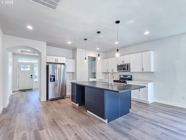 kitchen with visible vents, an island with sink, light wood-style flooring, stainless steel appliances, and a sink