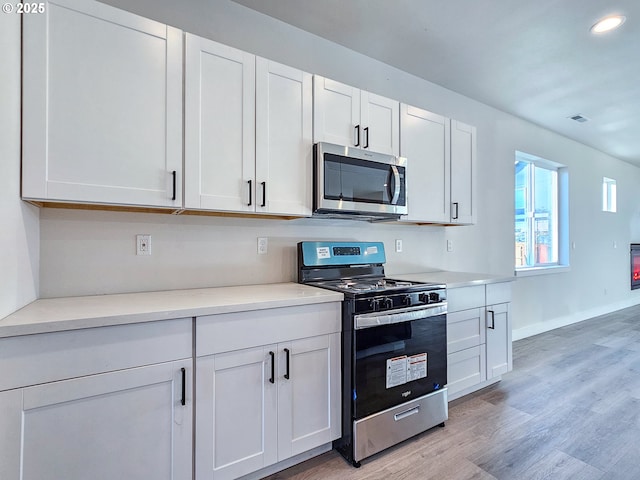 kitchen featuring visible vents, light countertops, stainless steel appliances, light wood-style floors, and white cabinetry