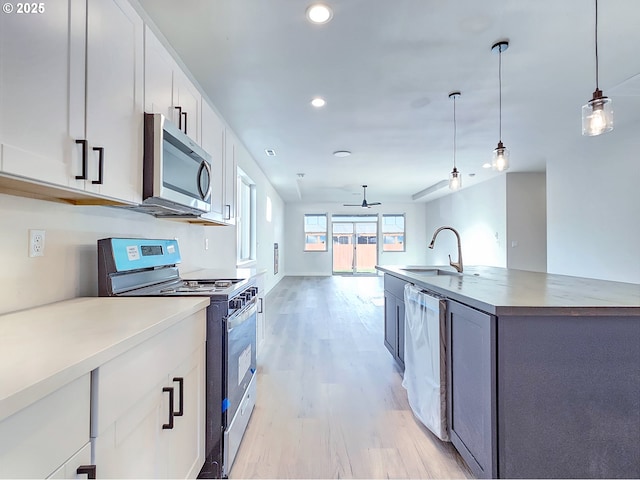 kitchen featuring open floor plan, pendant lighting, light wood-type flooring, white cabinets, and stainless steel appliances