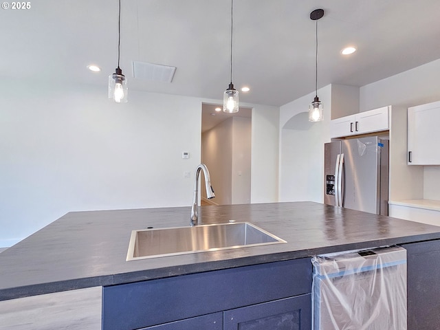 kitchen featuring pendant lighting, a sink, dark countertops, white cabinetry, and appliances with stainless steel finishes