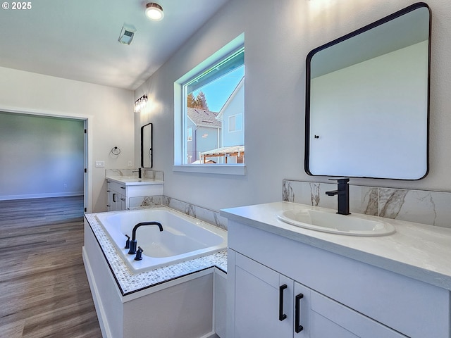 full bath featuring a sink, two vanities, wood finished floors, and a bath