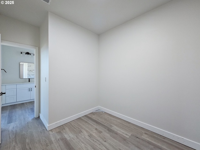 unfurnished room featuring visible vents, baseboards, light wood-style floors, and a sink