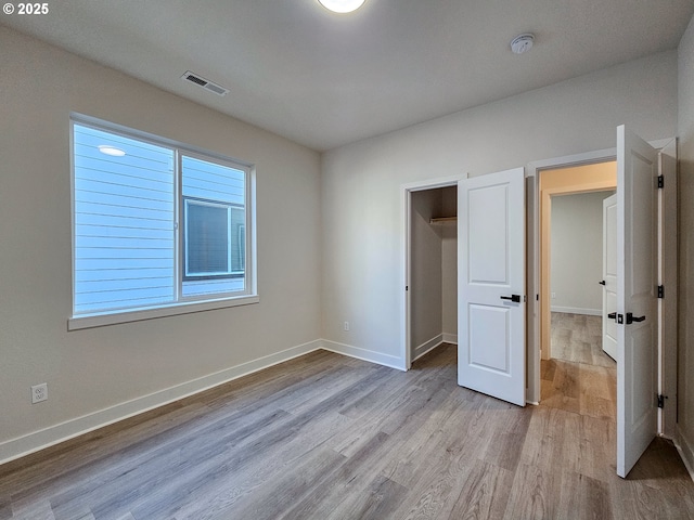 unfurnished bedroom featuring visible vents, baseboards, and wood finished floors