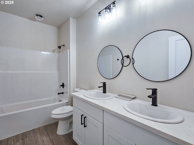 bathroom featuring toilet, wood finished floors, shower / tub combination, and a sink