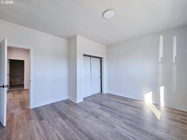 unfurnished bedroom featuring a closet, baseboards, and wood finished floors