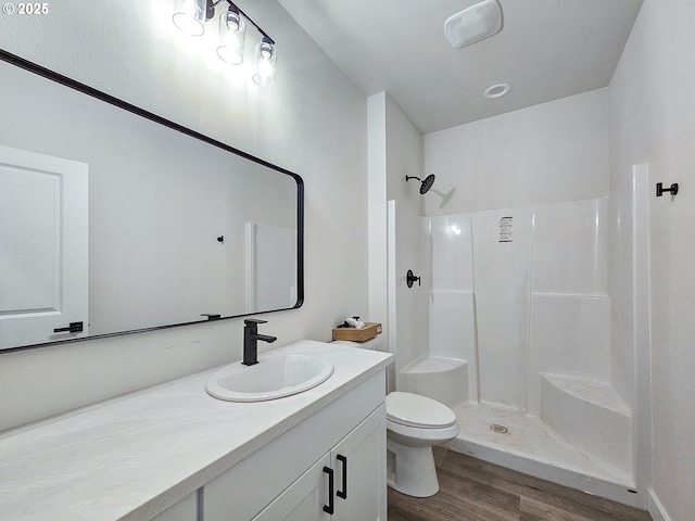 bathroom featuring vanity, toilet, wood finished floors, and a walk in shower