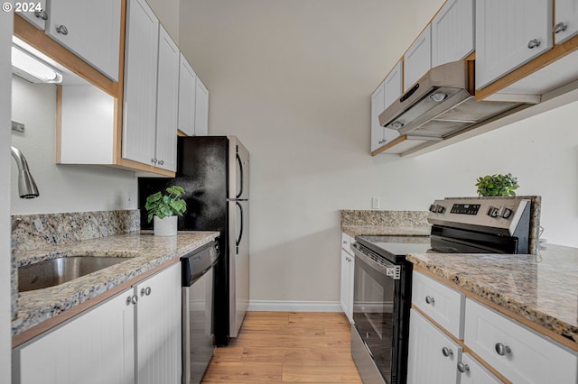 kitchen with sink, white cabinetry, light stone counters, light hardwood / wood-style floors, and appliances with stainless steel finishes