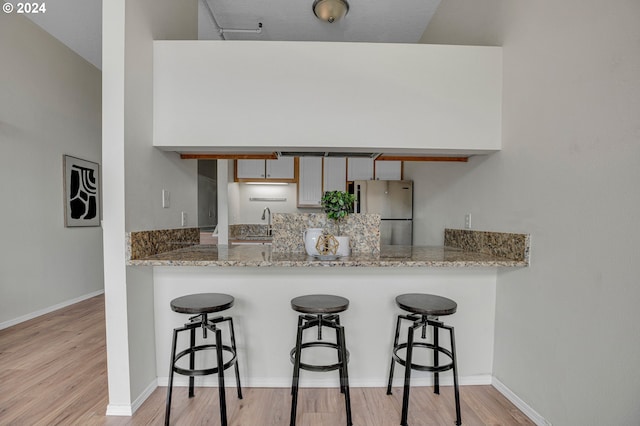 kitchen with a kitchen bar, kitchen peninsula, and stainless steel refrigerator