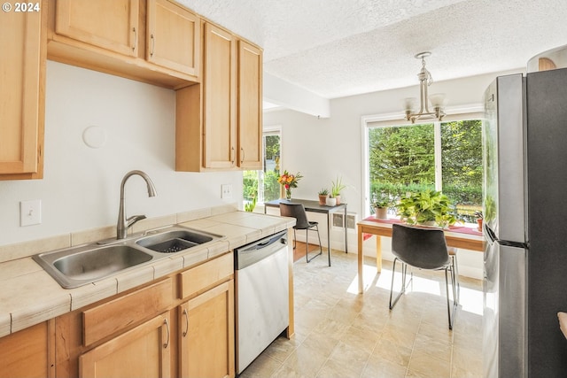 kitchen featuring sink, appliances with stainless steel finishes, hanging light fixtures, a textured ceiling, and tile countertops