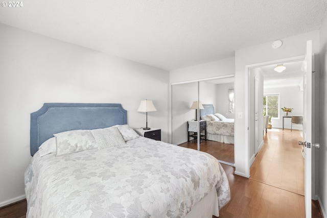 bedroom with a closet, dark hardwood / wood-style floors, and a textured ceiling