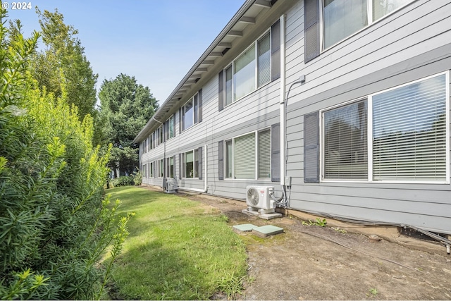 view of side of property featuring ac unit and a yard