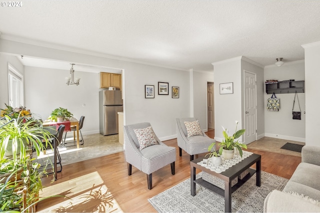 living room with a notable chandelier, crown molding, light hardwood / wood-style floors, and a textured ceiling