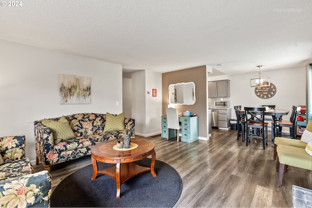 living area featuring an inviting chandelier, dark wood-style flooring, a textured ceiling, and baseboards
