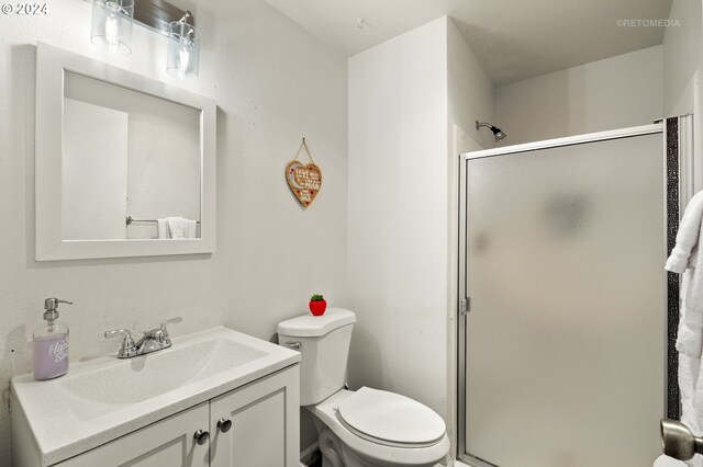 bathroom featuring a shower stall, toilet, and vanity