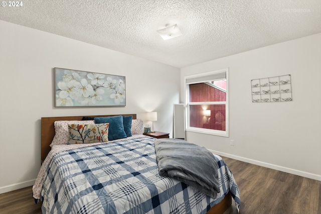 bedroom with baseboards, wood finished floors, and a textured ceiling